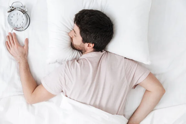 Alvó fiatalember reggel takaró alatt az ágyban fekszik — Stock Fotó