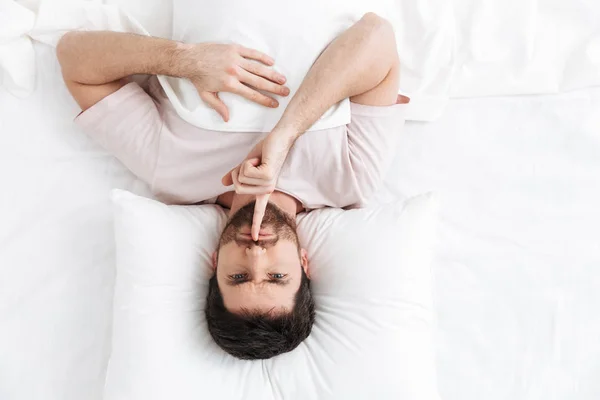 Yatakta yatan yakışıklı bir genç adamın üst görünümü — Stok fotoğraf