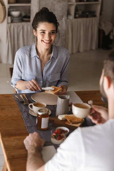 Imagen de una joven pareja morena comiendo juntos en la mesa mientras ha — Foto de Stock