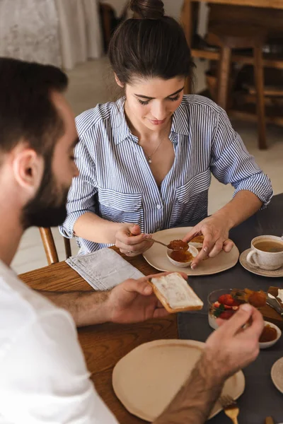 Imagem do casal morena satisfeito comendo juntos à mesa enquanto — Fotografia de Stock