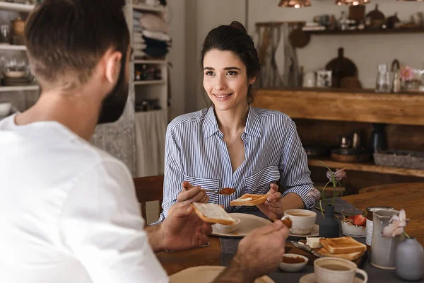 Imagen de la hermosa pareja morena comiendo juntos en la mesa mientras — Foto de Stock