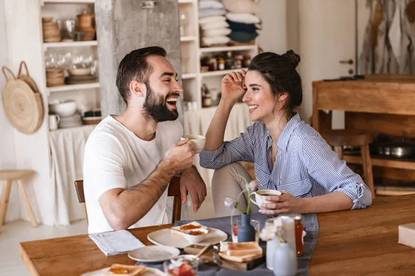 Image of modern brunette couple eating breakfast together while — Stock Photo, Image