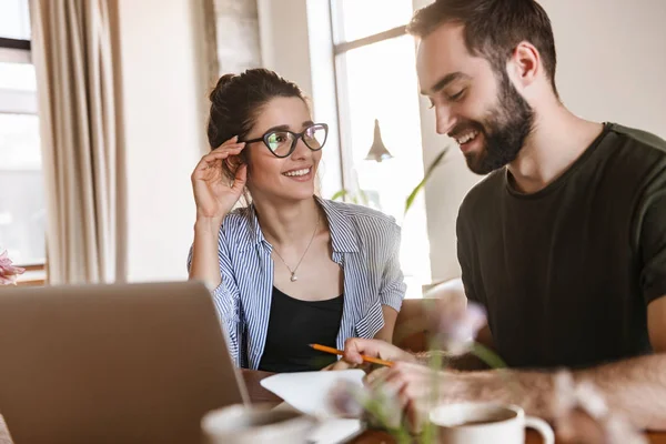 Immagine di una coppia bruna gioiosa che lavora insieme sul computer portatile mentre — Foto Stock