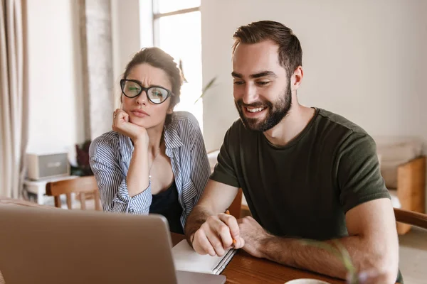 Immagine di una moderna coppia bruna che lavora insieme sul computer portatile mentre — Foto Stock