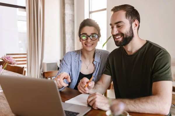 Imagen de la alegre pareja morena trabajando juntos en el portátil whi —  Fotos de Stock