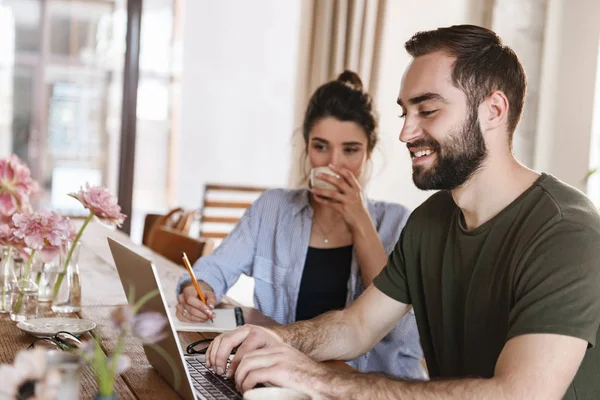 Immagine di adorabile coppia bruna che lavora sul computer portatile insieme whi — Foto Stock