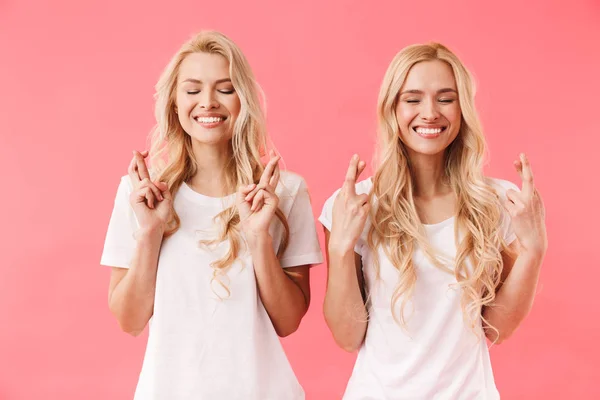 Lächelnde blonde Zwillinge in T-Shirts, die gemeinsam beten — Stockfoto