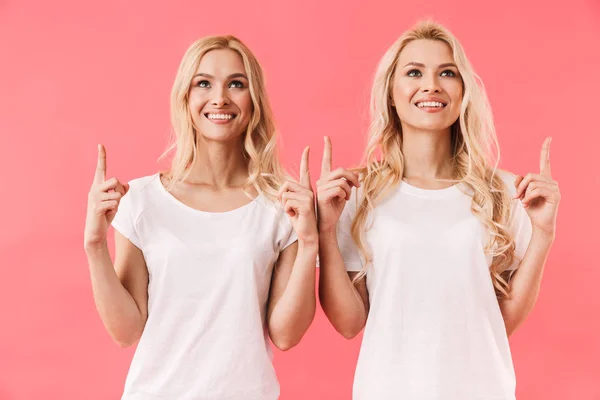 Uśmiechnięte bliźnięta noszenie w koszulkach wskazując i patrząc — Zdjęcie stockowe