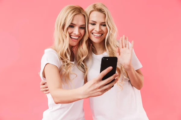 スマートフォンでビデオ通話で話すTシャツを着た双子の笑顔 — ストック写真