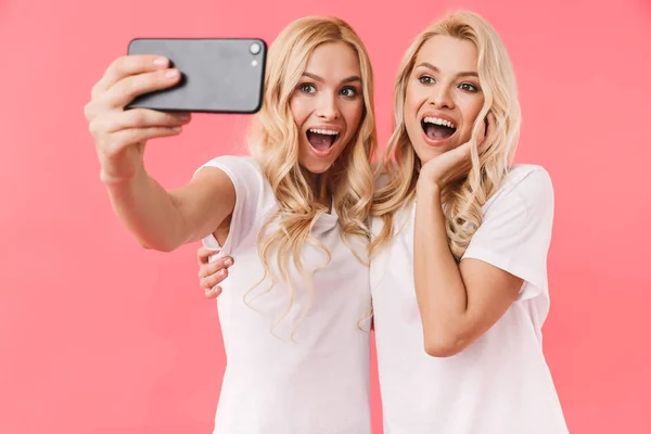 Surpreendido feliz loira gêmeos vestindo em t-shirts fazendo selfie — Fotografia de Stock