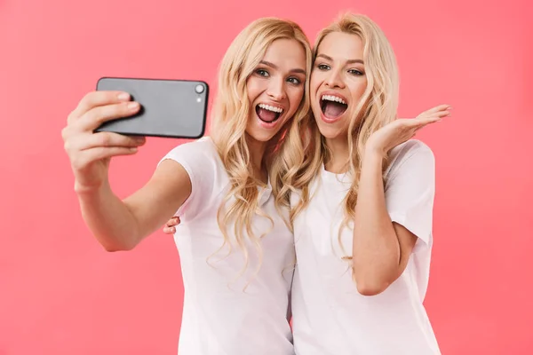 Gemelos rubias alegres usando camisetas haciendo selfie en el teléfono inteligente — Foto de Stock