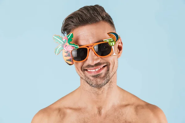 Emocionado hombre adulto feliz en traje de baño posando aislado sobre fondo de pared azul con gafas de sol . — Foto de Stock