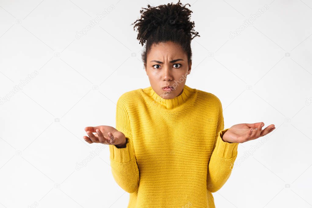 Beautiful young african confused woman posing isolated over white wall background.