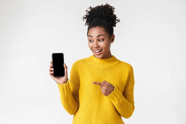 Hermosa joven africana emocionada mujer emocional posando aislado sobre fondo de pared blanca que muestra la pantalla del teléfono móvil . —  Fotos de Stock