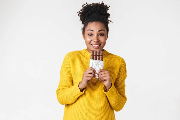 Mooie jonge Afrikaanse opgewonden emotionele gelukkige vrouw poseren geïsoleerd over witte muur achtergrond Holding snoepjes chocolade. — Stockfoto