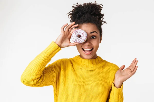Αφρικανική χαρούμενη γυναίκα που παρουσιάζουν απομονωμένη πάνω από λευκό τοίχο φόντο κρατώντας γλυτάκια ντόνατς. — Φωτογραφία Αρχείου