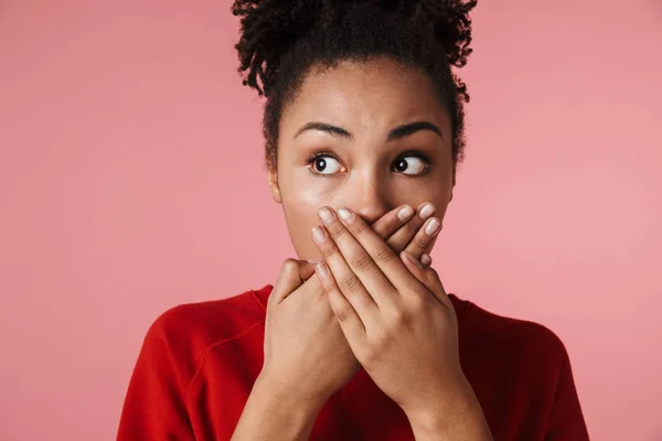 Sorprendida joven africana asustada posando aislada sobre fondo de pared rosa cubriendo la boca . —  Fotos de Stock