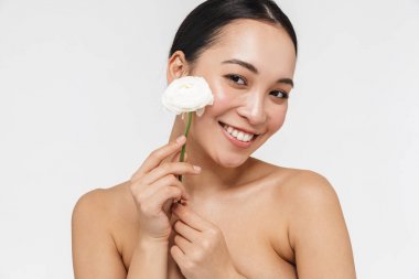 Sağlıklı cilt güzel genç güzel Asyalı kadın çıplak beyaz duvar arka plan tutan çiçek.