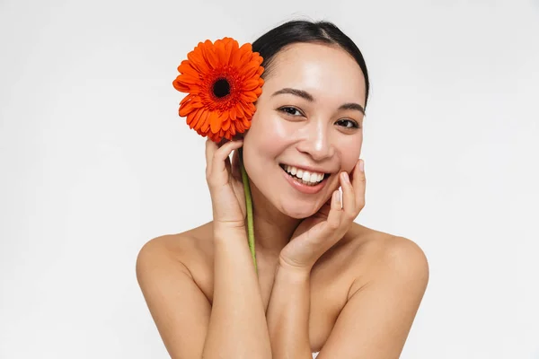 Hermosa joven bonita mujer asiática con piel sana posando desnuda aislada sobre fondo de pared blanca sosteniendo flor . — Foto de Stock
