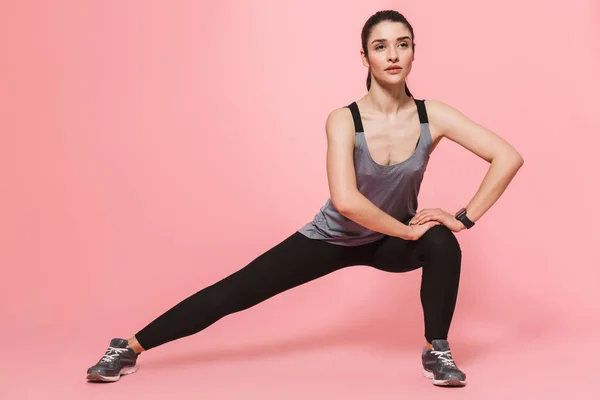 Incrível bela jovem bonita fitness mulher fazer exercícios esportivos isolados sobre fundo de parede rosa . — Fotografia de Stock