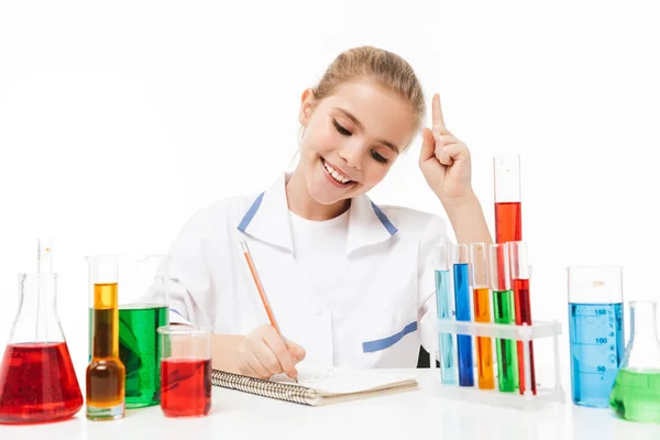 Beeld van mooie school meisje in wit laboratorium jas maken c — Stockfoto