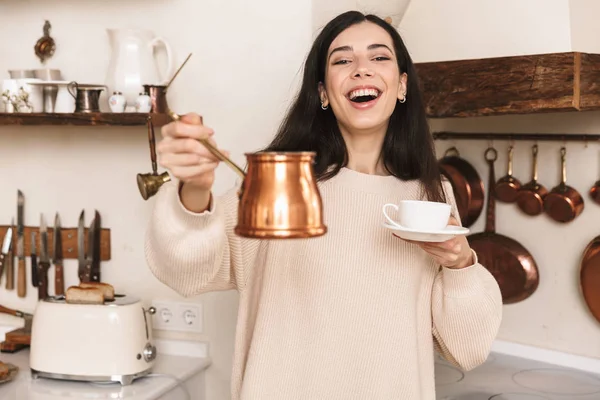 Chica joven encantadora tomando una taza de café en la cocina —  Fotos de Stock