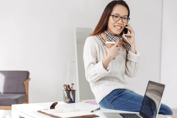 Lachende Aziatische zakenvrouw in brillen praten door smartphone — Stockfoto