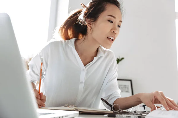 Концентрована усміхнена азіатська бізнес-леді читає документи — стокове фото
