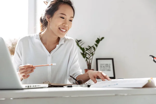 Lächelnde asiatische Geschäftsfrau beim Lesen von Dokumenten am Tisch — Stockfoto