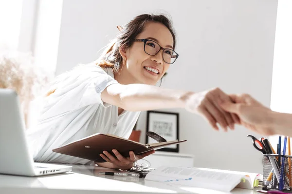 Щаслива азіатська бізнес жінка в окулярах на зустрічі робить рукостискання — стокове фото