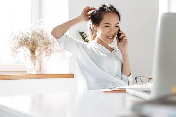 Весела азіатська бізнес-леді розмовляє по смартфону — стокове фото