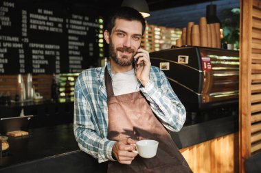 Portre bu genç barista adam Talking üzerinde Cellphone içinde sokak CAF
