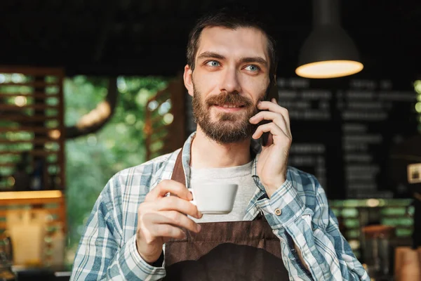 Portrait of attractive barista guy talking on cellphone in stree — Stock Photo, Image