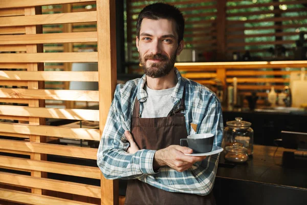 Retrato de tipo barista homem segurando xícara de café enquanto trabalhava — Fotografia de Stock