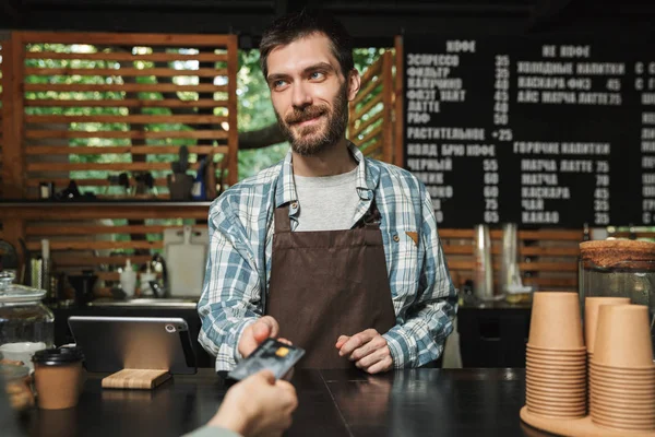 Portret szczęśliwy człowiek Barista biorąc karty kredytowej od klienta w — Zdjęcie stockowe