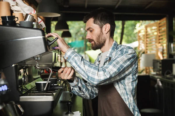 Imagen del joven camarero haciendo café mientras trabajaba en la cafetería o —  Fotos de Stock
