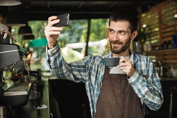 Porträt des brünetten Barista-Mannes beim Selfie-Fotografieren während der Arbeit — Stockfoto