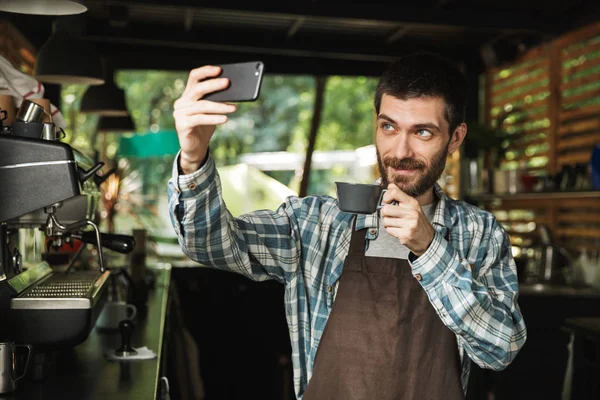 Retrato de barista caucásico tomando foto selfie mientras trabaja —  Fotos de Stock