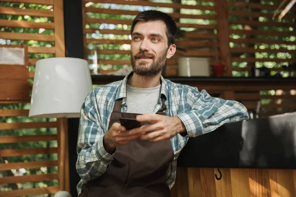 Imagen del camarero europeo sentado en el bar y usando el celular —  Fotos de Stock