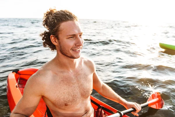 Smiling young sportsman kayaking — Stock Photo, Image