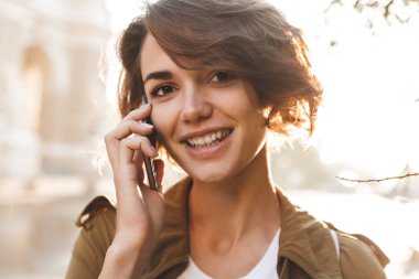 Sevimli genç inanılmaz kadın güzel bahar gününde parkta açık havada yürüyen cep telefonu ile konuşurken.