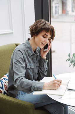 Kapalı kafe masasında oturan çekici genç kadın