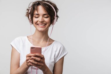 Akıllı telefonu tutan temel tişörtte gülümseyen kadının görüntüsü