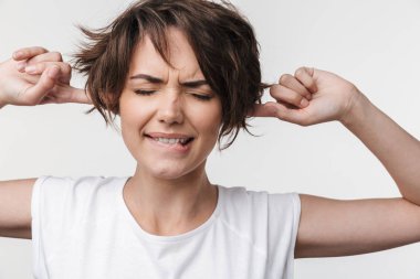 Oldukça hoşnutsuz stresli kadın yüksek sesle nedeniyle kulakları kapsayan beyaz duvar arka plan üzerinde izole poz.