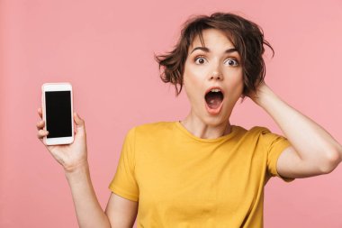 Şok genç güzel kadın cep telefonu kullanarak pembe duvar arka plan üzerinde izole poz.