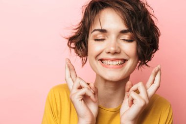 Heyecanlı güzel kadın pembe duvar arka plan üzerinde izole poz umutlu yapmak jest parmakları geçti lütfen.