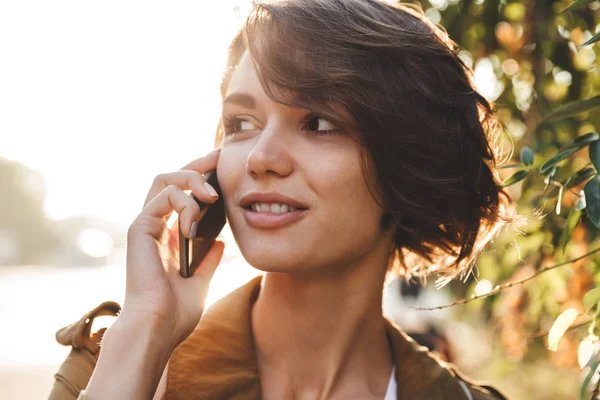 Bonito jovem mulher incrível andando ao ar livre no parque em belo dia de primavera falando por telefone celular . — Fotografia de Stock