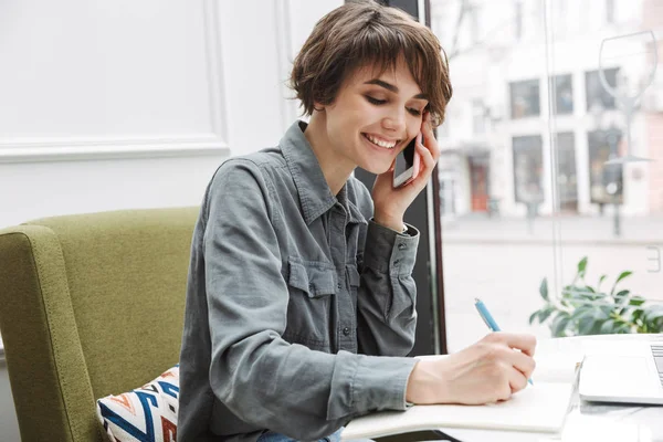 Attractive young woman sitting at the cafe table indoors — Stock Photo, Image