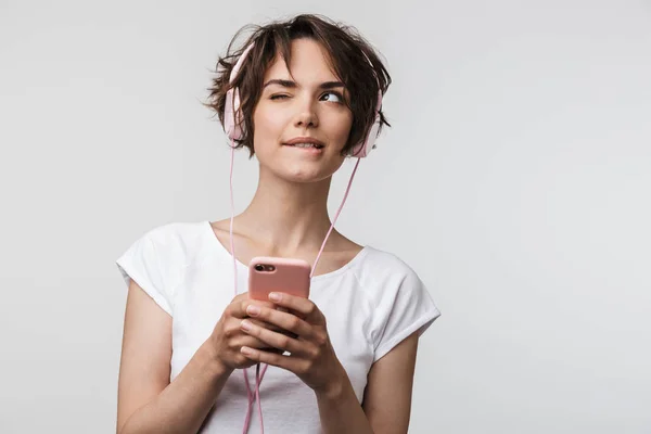 Bild av ung kvinna i grundläggande t-shirt hålla smartphone medan l — Stockfoto