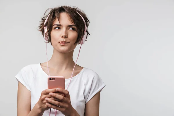 Imagen de mujer complicada en camiseta básica sosteniendo el teléfono inteligente mientras — Foto de Stock